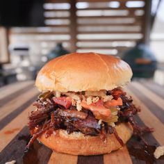 a pulled pork sandwich sitting on top of a wooden table