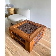 a wooden box sitting on top of a hard wood floor next to a white couch