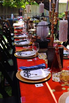 a long table is set with place settings and wine glasses on it for an outdoor dinner party