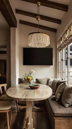 a wooden table sitting in front of a window next to a bench with pillows on it