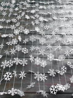 snowflakes are hanging from a wire on a wooden deck with string attached to it