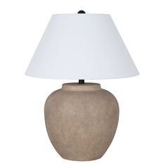 a lamp that is on top of a white table cloth next to a brown vase