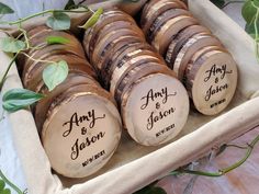 wood slices with names on them are arranged in a wooden box next to greenery