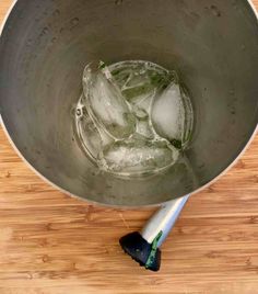 a metal bowl filled with ice on top of a wooden table