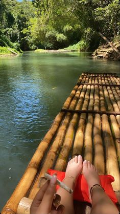 someone is laying down on a bamboo raft in the middle of a body of water