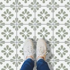 a person standing on a tiled floor with their feet propped up in the middle of it