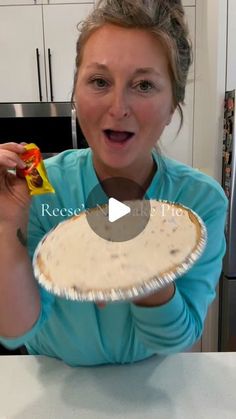 a woman holding up a piece of food in front of her face and making a funny face