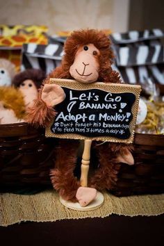 a stuffed monkey holding a sign that says let's go bananas adopt a monkey