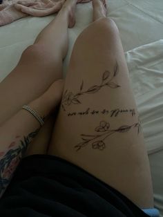 a woman laying on top of a bed with her legs crossed and tattoos on her leg