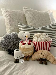 stuffed animals are sitting on a bed with popcorn and cakes in the shape of animals