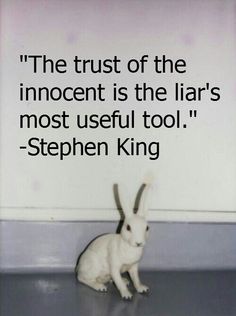 a small white rabbit sitting on top of a wooden floor next to a sign that says,'the trust of the innocent is the lar's most useful tool stephen king