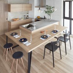 a modern kitchen with an island and dining table set for four in front of the window