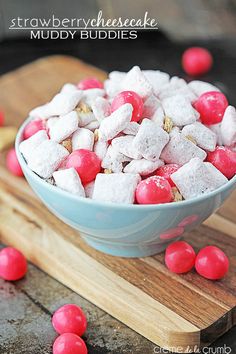 a bowl filled with red and white marshmallows on top of a wooden cutting board