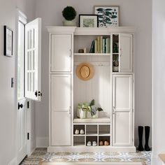 a white cupboard with shoes and hats on top in a room next to a door