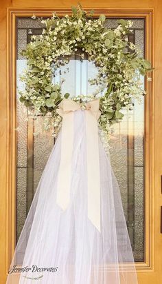 a wedding dress hanging on a door with a veil over it's front window