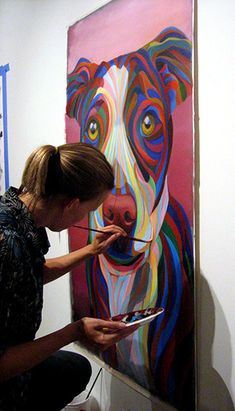 a woman is painting a dog's face on a canvas