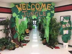 a welcome to the jungle sign is on display in a hallway with potted plants