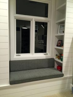 a window seat in the corner of a room next to a book shelf filled with books