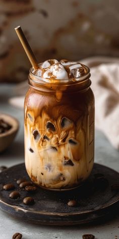 there is a drink in a glass with ice and coffee beans on the table next to it