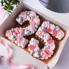 pink and silver decorated cookies in a box with ribbon on the table next to it