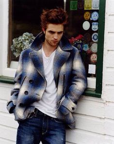 a young man leaning against the side of a building