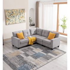 a living room with a gray sectional couch and yellow pillows on top of the rug