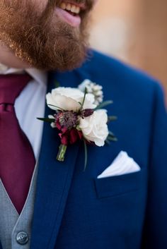 a close up of a man wearing a suit and tie with flowers on his lapel