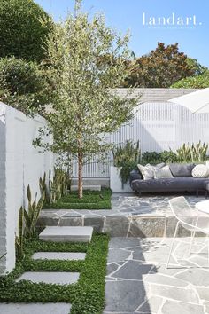 an outdoor seating area with stone steps and grass in the middle, next to a white fence