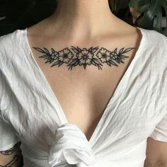 a woman with a tattoo on her chest is wearing a white shirt and has an open back