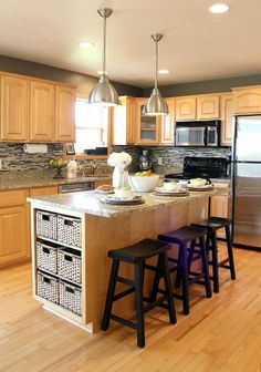 a kitchen with wooden cabinets and black appliances in the center is an island that has three stools on it