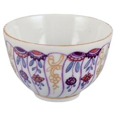 a white bowl with purple and orange designs on the rim, sitting in front of a white background