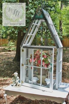 an old window is transformed into a miniature house with flowers in the front and side