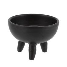 a black bowl sitting on top of a wooden stand