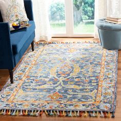 a living room area with a blue couch, chair and large rug on the floor