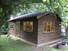 a small wooden cabin sitting in the middle of a yard next to a large tree