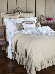 a bed with ruffled bedspread and pillows in a bedroom next to a chair