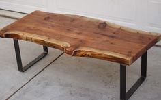 a wooden table with metal legs sitting on the concrete floor next to a garage door