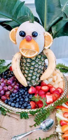 a plate with fruit and a monkey made out of bananas, pineapples, grapes, strawberries, kiwis