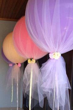 three balloons with tulle and flowers on them hanging from the ceiling in front of a mirror