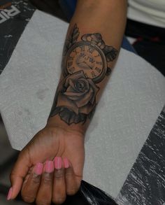 a woman's arm with a rose tattoo on it and a clock in the middle