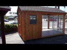 a small wooden dog house on the side of the road in front of a parking lot