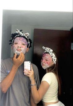 a man and woman with face paint on their faces are taking a selfie in front of a mirror