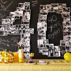 a table topped with pictures and balloons next to a chalkboard wall covered in writing