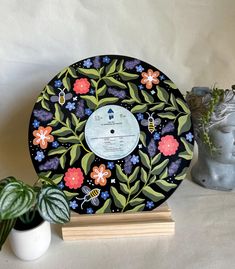 a record sitting on top of a wooden stand next to a potted plant and vase