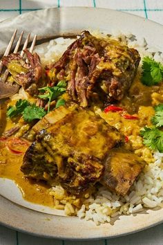 a white plate topped with rice and meat covered in gravy, garnished with cilantro