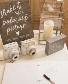 a table topped with two cameras next to a sign that says shake it like a polaroid picture