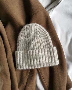 a white hat laying on top of a brown jacket