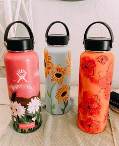 three colorful water bottles sitting next to each other on top of a white tablecloth