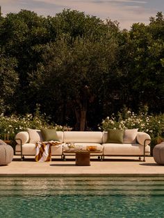 a couch sitting on top of a pool next to a lush green forest