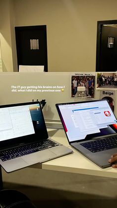 two laptops sitting on top of a desk next to each other in front of pictures